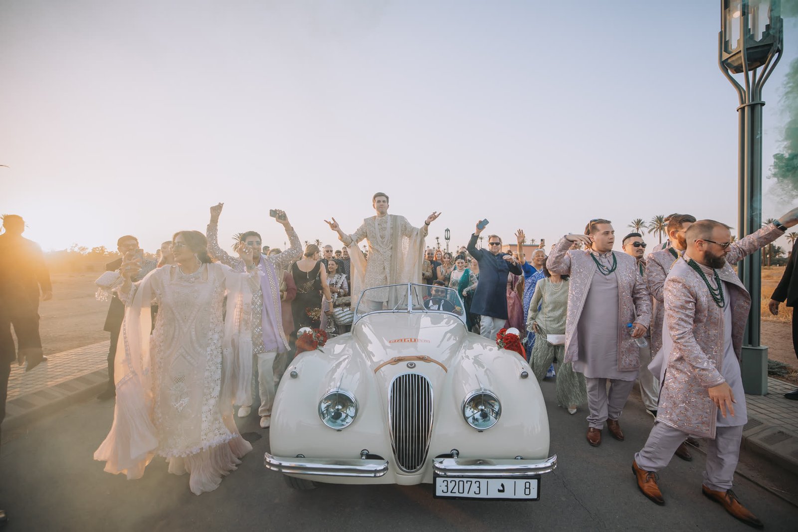 The Baraat at sunset with a vintage white roadster