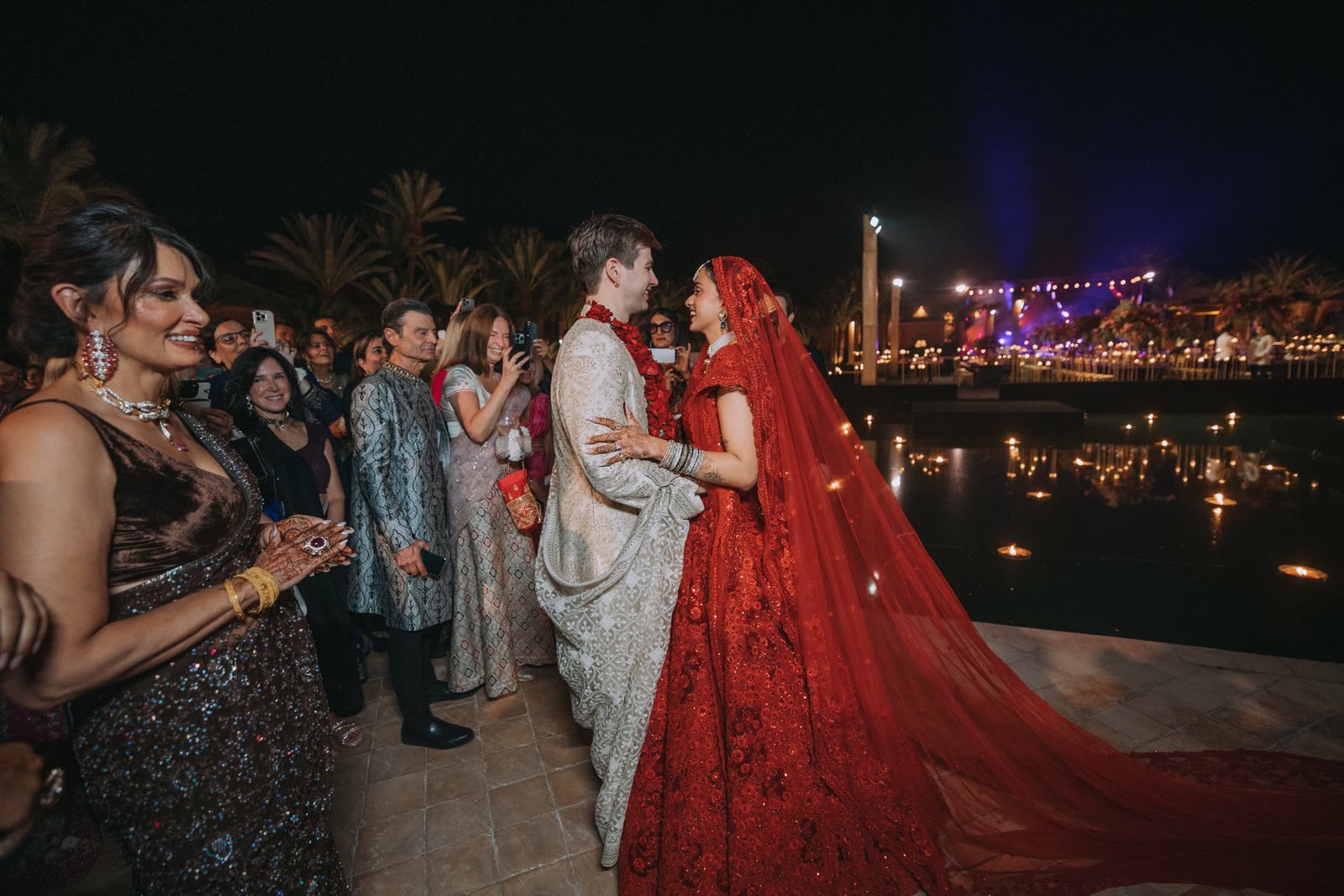 Henna and Ben greeting guests beside the water at night