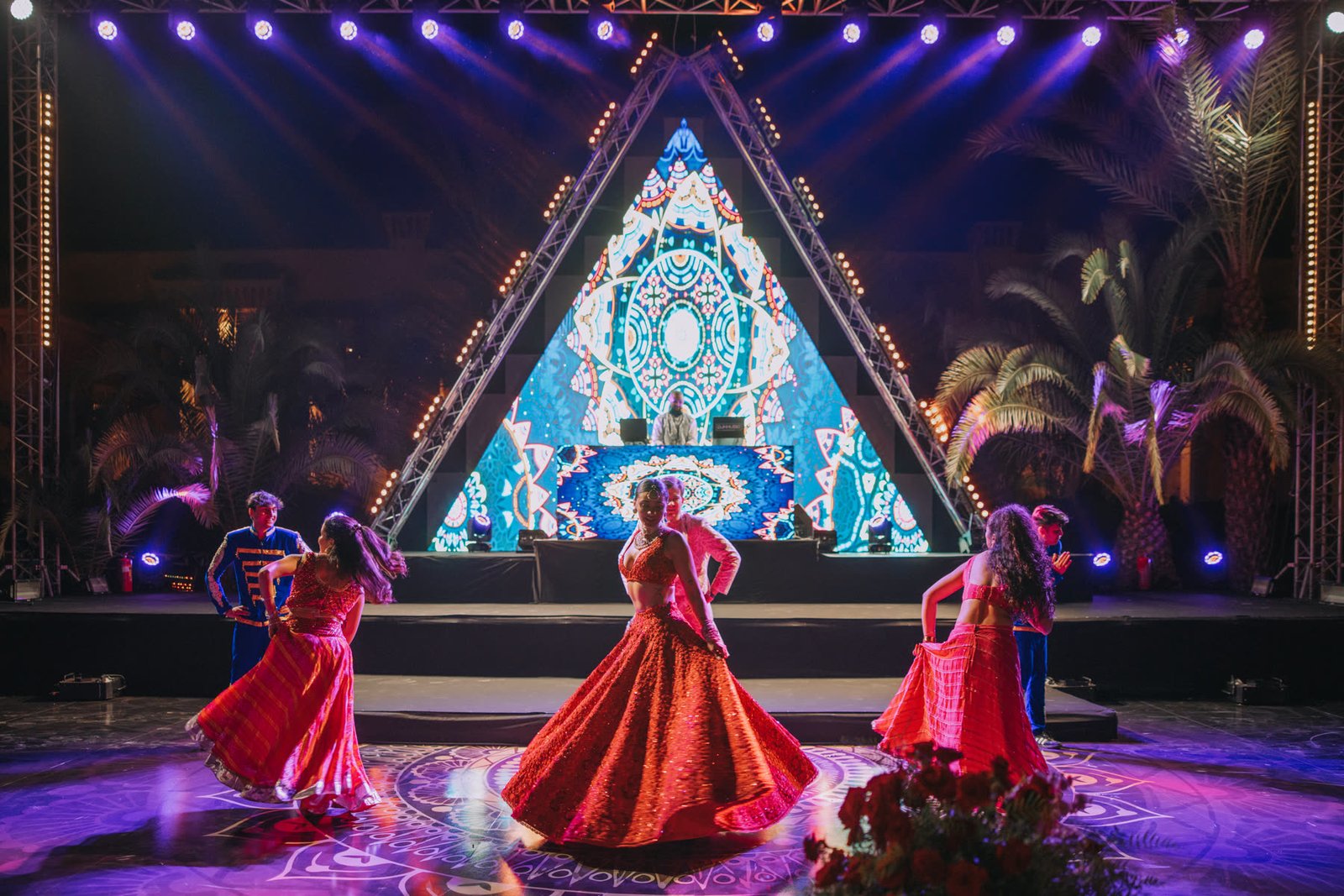 Sangeet performance on stage in front of an illuminated triangle