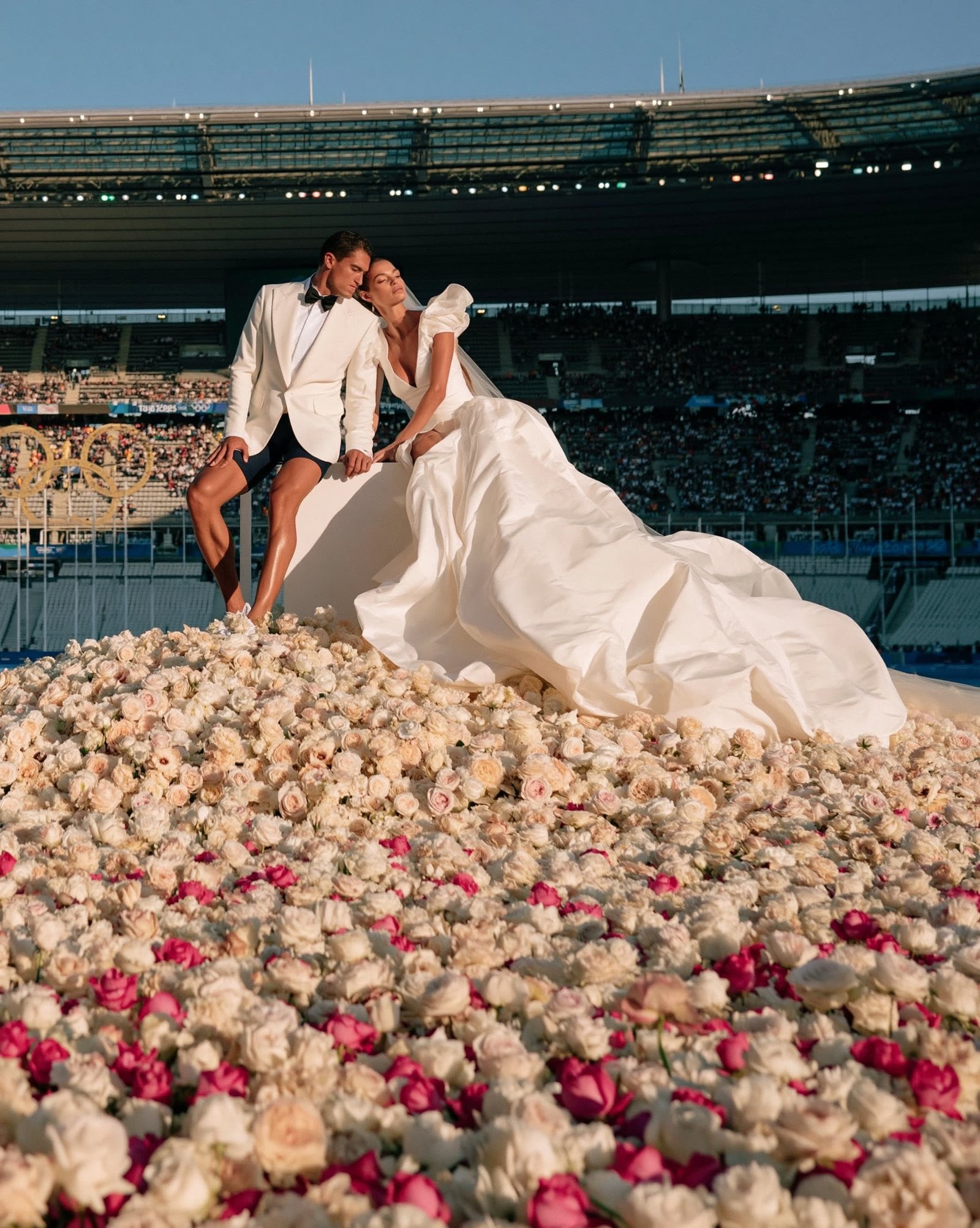 Bride with a sweeping train stretched across a flower-covered stadium field