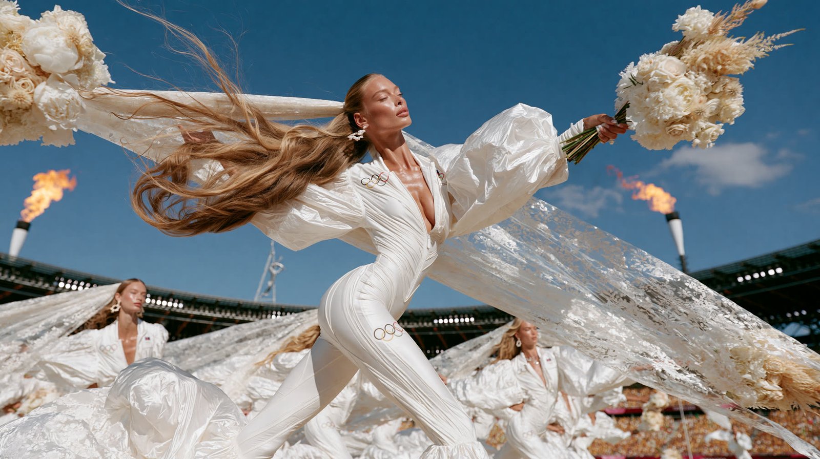 Bride as an Olympic torchbearer in a white jumpsuit, the cauldron flame burning behind her