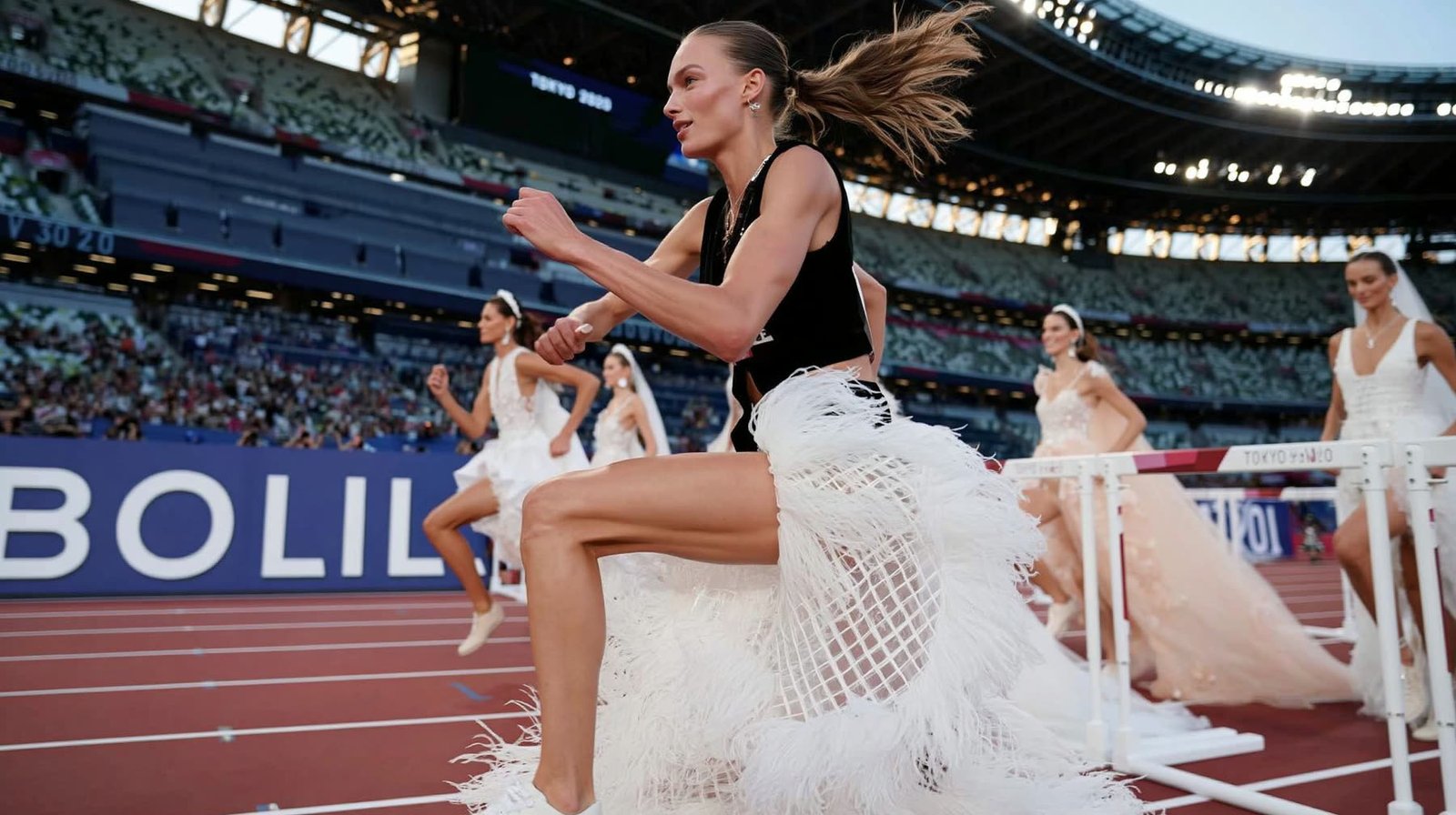 An athlete in black clearing a hurdle past a row of brides in a packed Olympic stadium